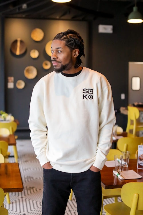 Man wearing white sweatshirt with black embroidered Soko logo