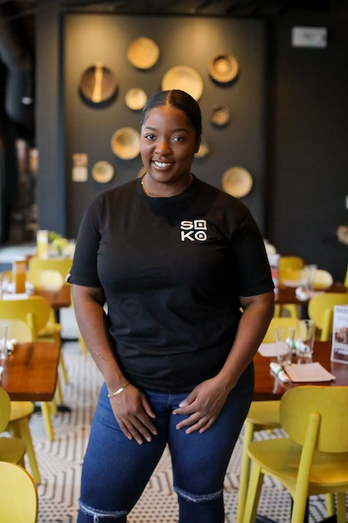 Woman wearing black t-shirt with white embroidered SOKO logo