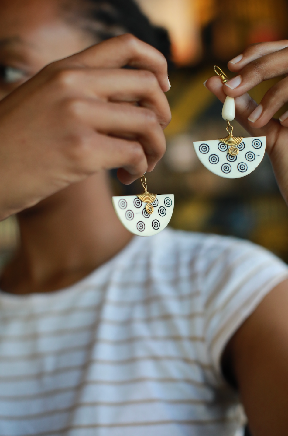 Girl holding up white half circle earrings made in Africa